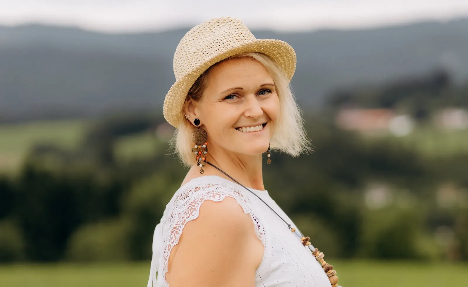 Iris Pointinger lächelnd vor der Landschaft des Bayerischen Waldes